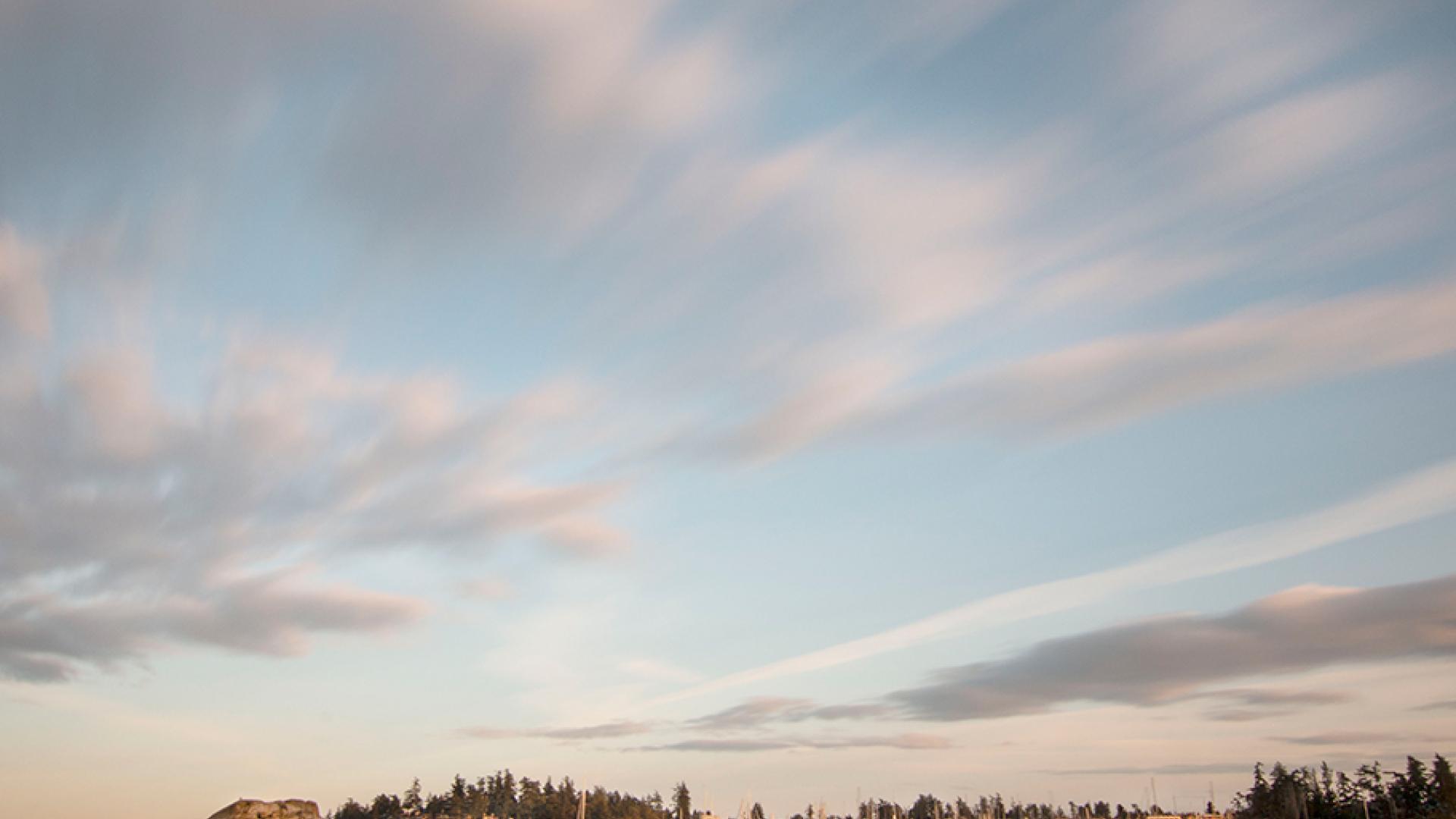 Calm seascape at sunset with blurred clouds and distant shoreline.