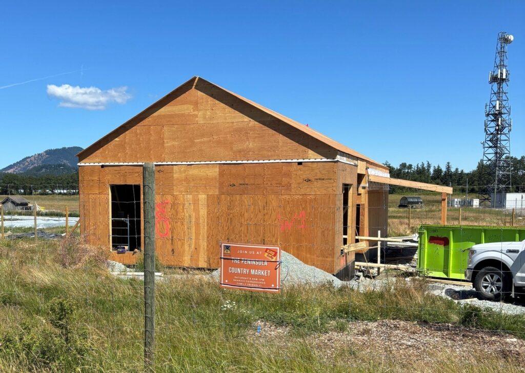 Newly constructed wooden house with a blue sky and distant cell tower in the background.